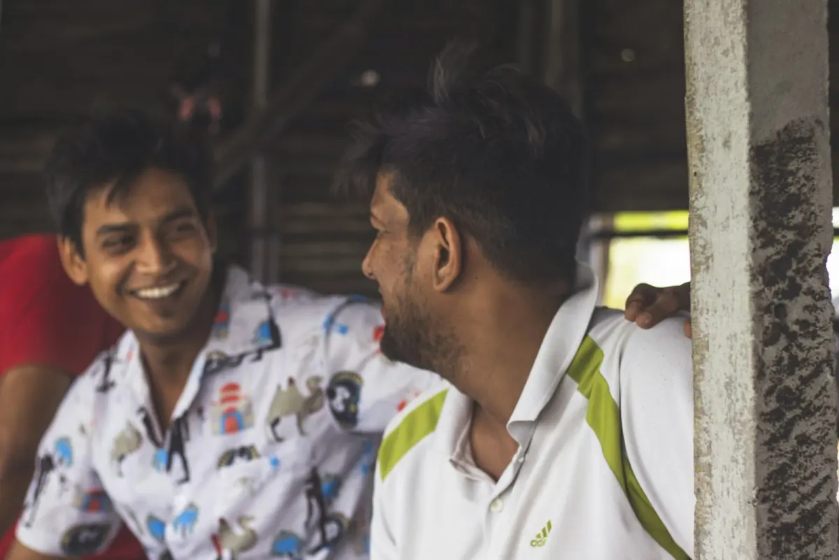 Two friends laughing together, one with an arm round the other