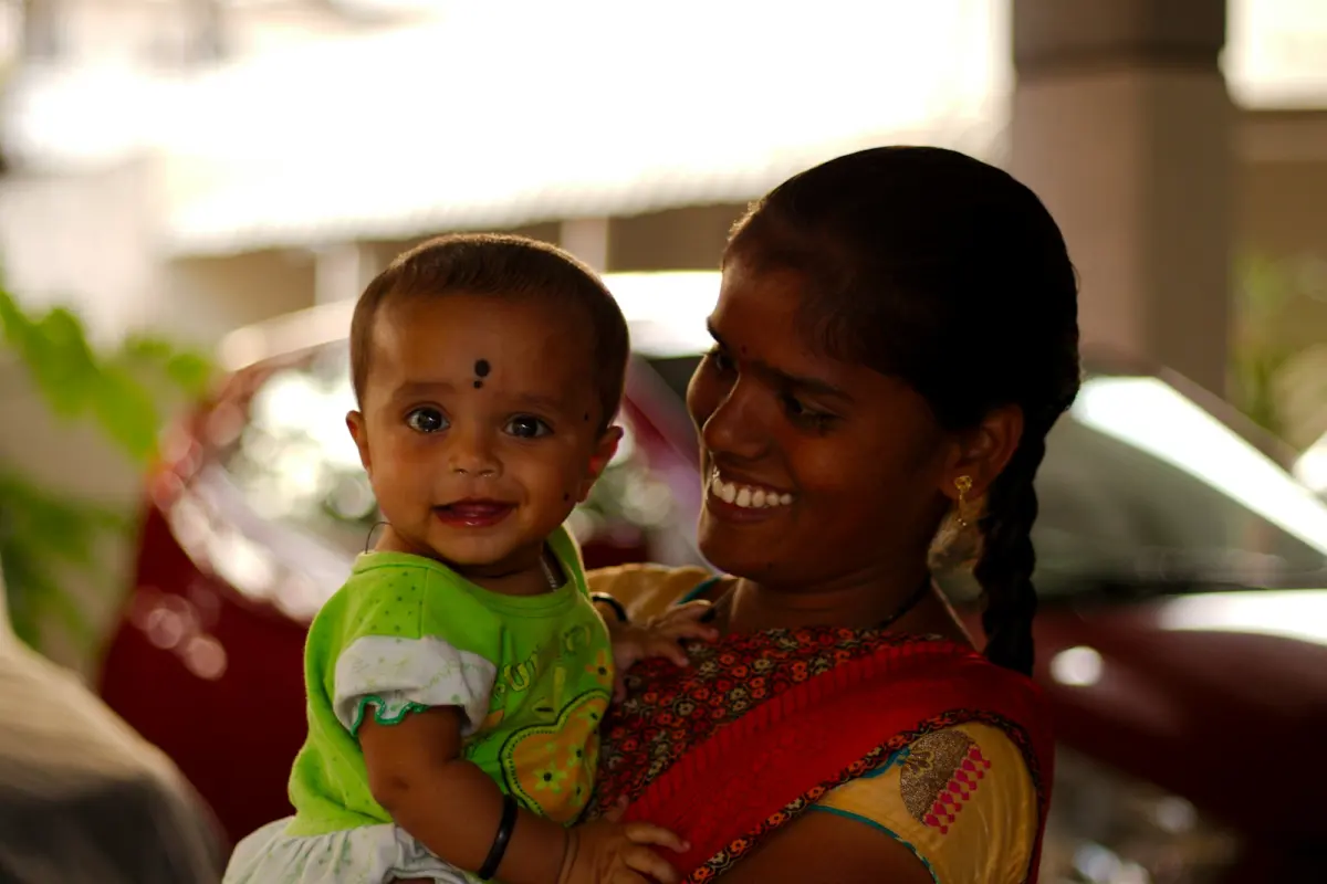 A mother laughing with the baby she is holding