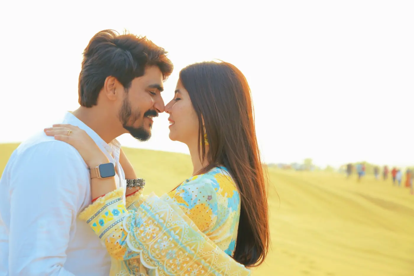A young couple nose to nose, laughing, in bright evening light